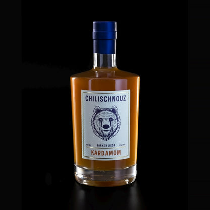Stimmungsbild Chilischnouz Kardamom Likör – Flasche mit Kardamom, Chili und Pfefferkörnern atmosphärisch arrangiert, warmes Licht