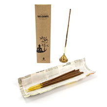 Anwendungsbild Paropakaram Nag Champa – glimmendes Räucherstäbchen, natürliche Zutaten und Recycling-Verpackung dekorativ arrangiert